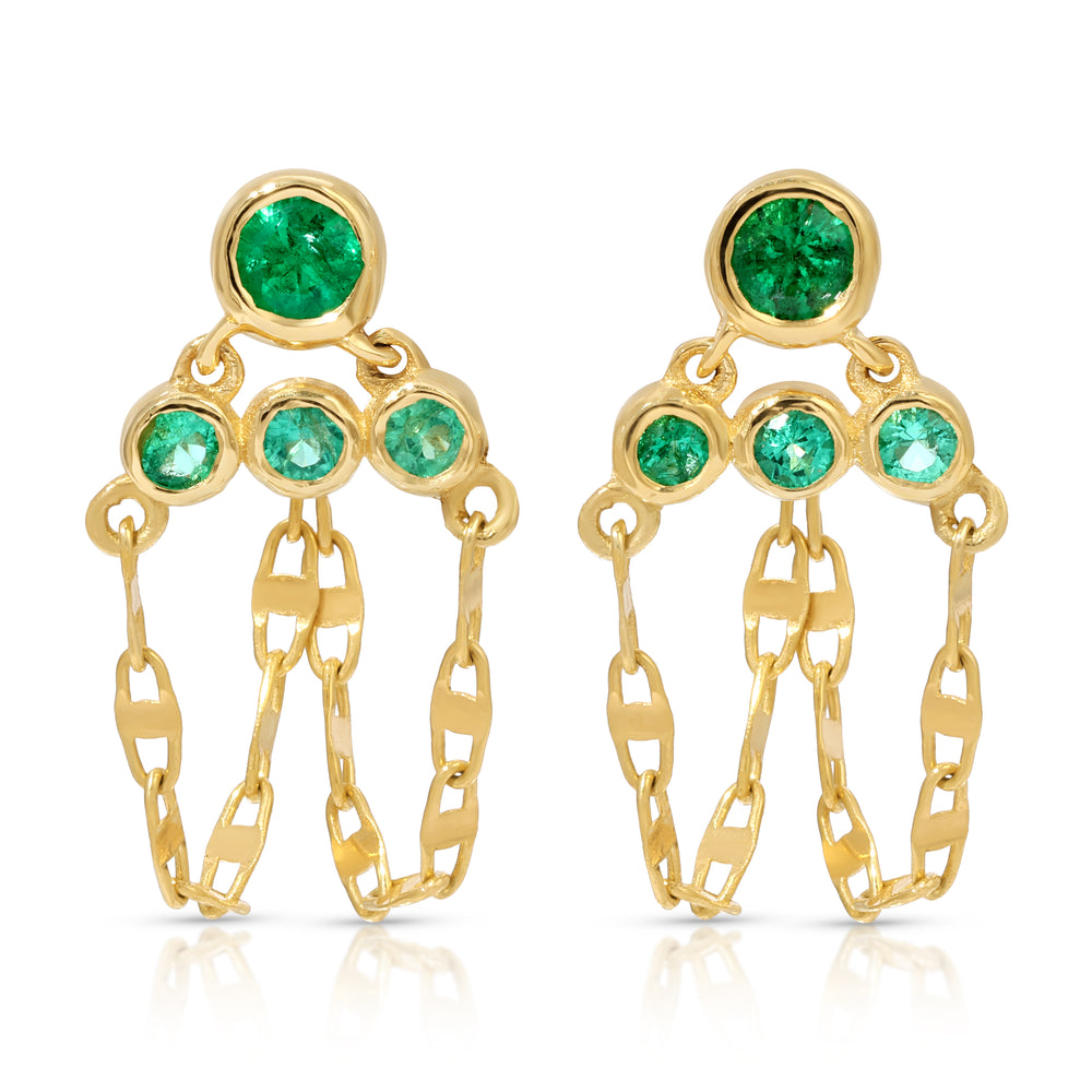 A pair of handcrafted 14k yellow gold post drop earrings featuring four round bezel-set green emerald gemstones on each earring arranged in a tiered, triangular cluster. Three delicate loops of mariner link chain suspend gracefully beneath the stones, creating a fluid dangle fringe against a clean white background.